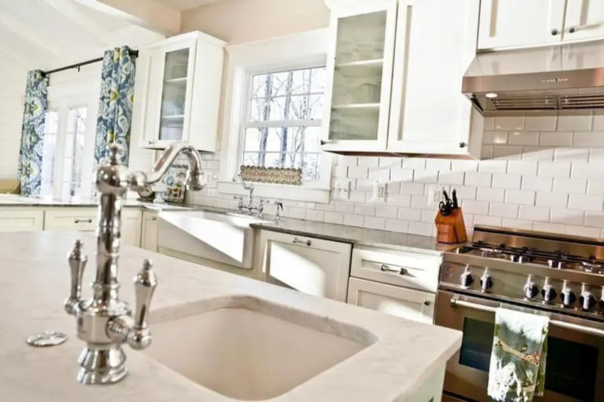 Kitchen with marble countertops, chrome faucet and subway tiles