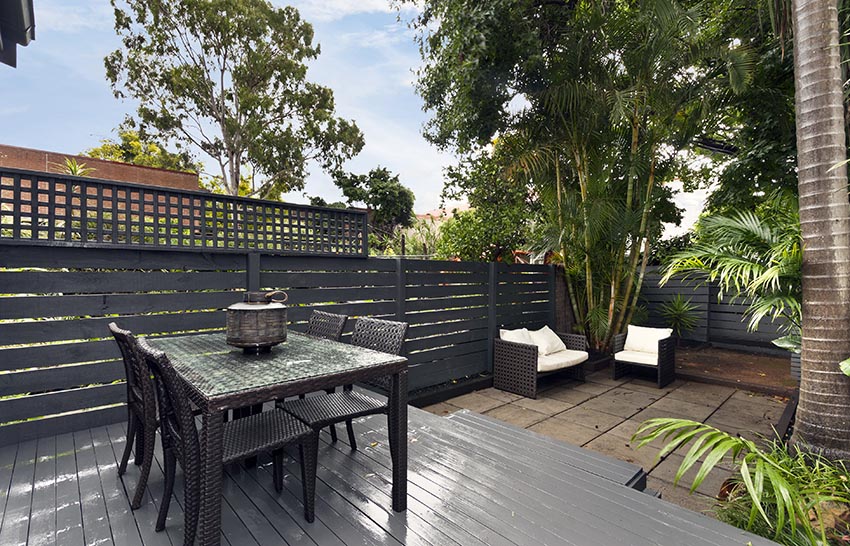 Deck with fence made of horizontal wood slats and furniture with white cushions