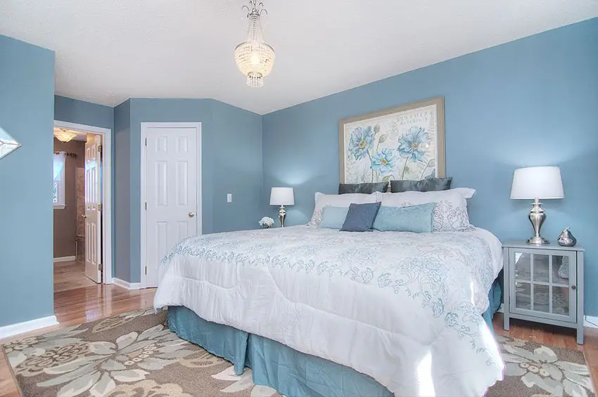 White and blue bedroom, light wood floors and flower area rug