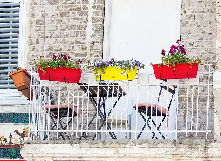 Colorful balcony flower boxes on metal railing brick house