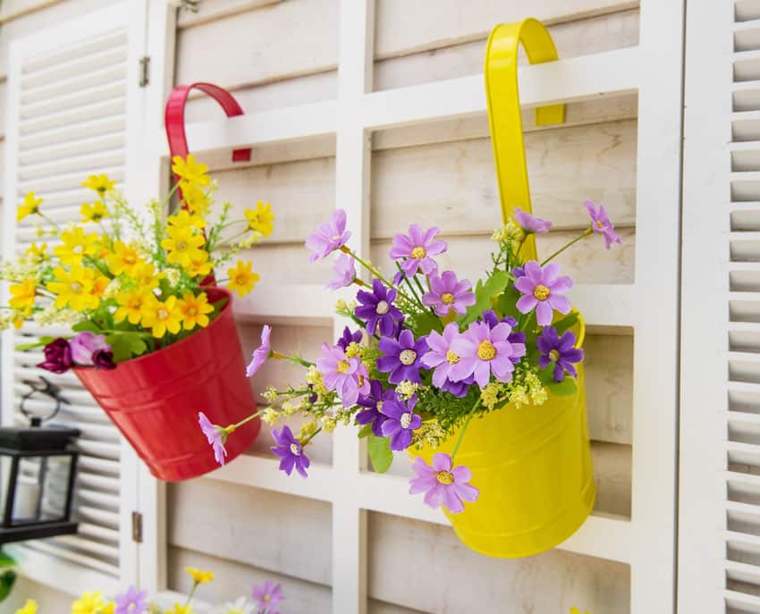 Colorful hanging plant pails on fence with pretty cut flowers