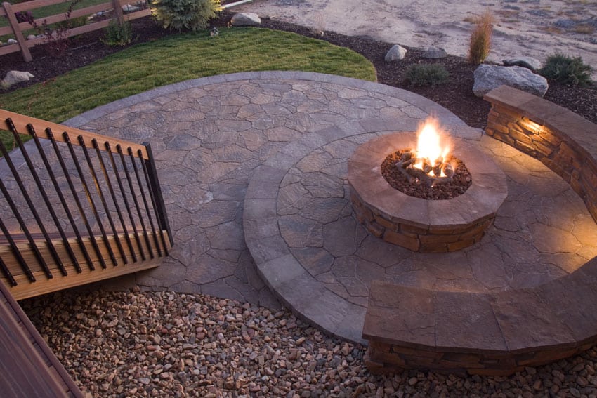 Concrete patio with flagstone design and firepit with curved bench