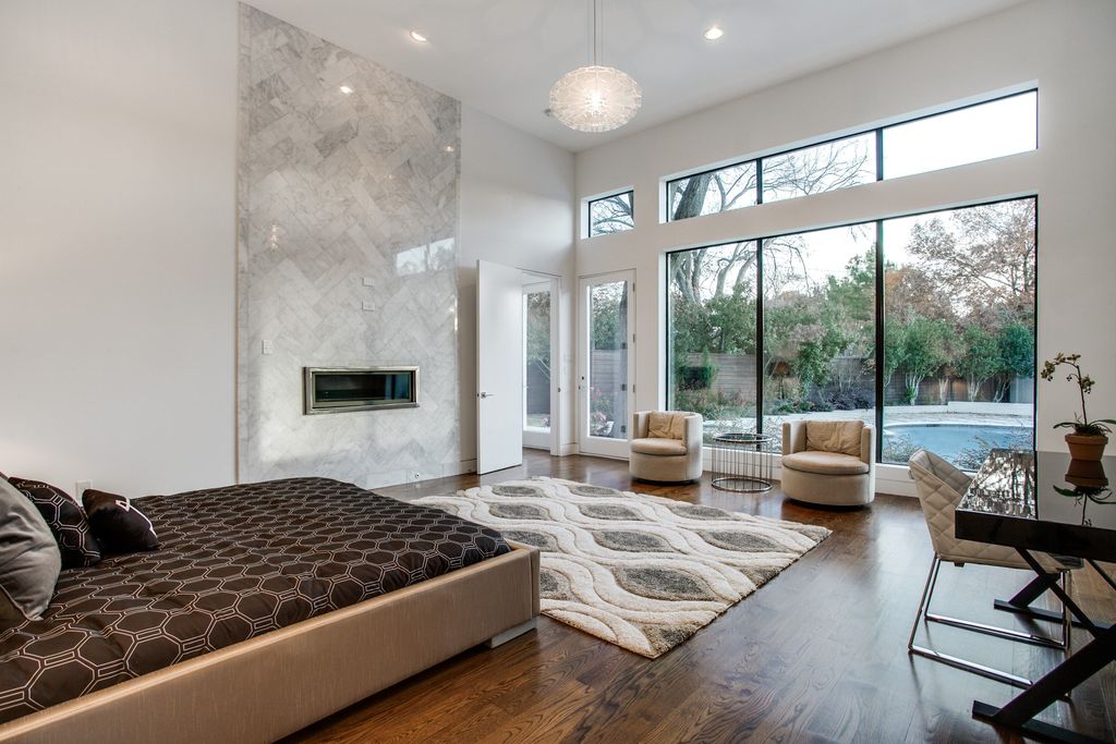 Contemporary bedroom with queen size bed, wood floors, round pendant light and backyard views