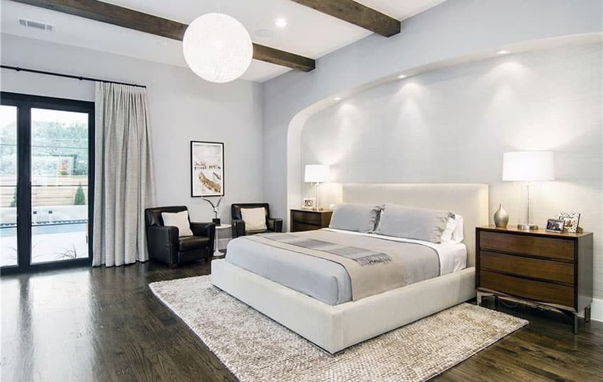 Contemporary bedroom with upholstered bed, wood flooring and beam ceiling