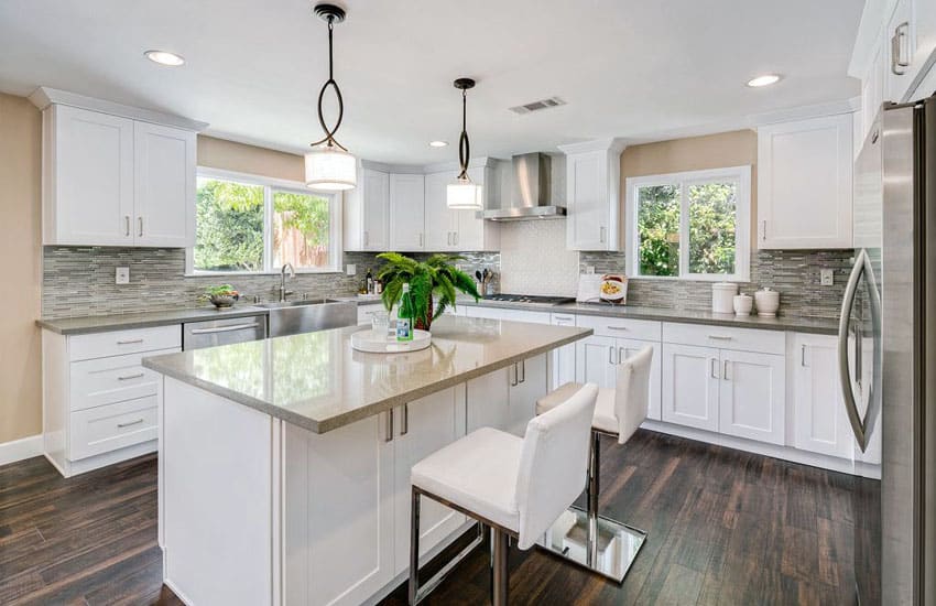 Contemporary kitchen with white shaker cabinets cream quartz countertops and glass mosaic tile backsplash