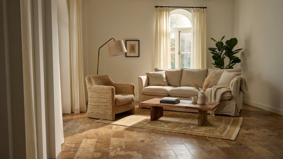 Living room with linen sofa, woven armchair and honey toned cork plank flooring
