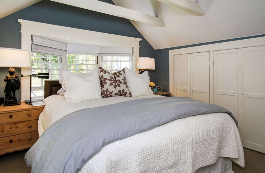Cottage style bedroom with dark blue paint and painted white vaulted ceiling with beams