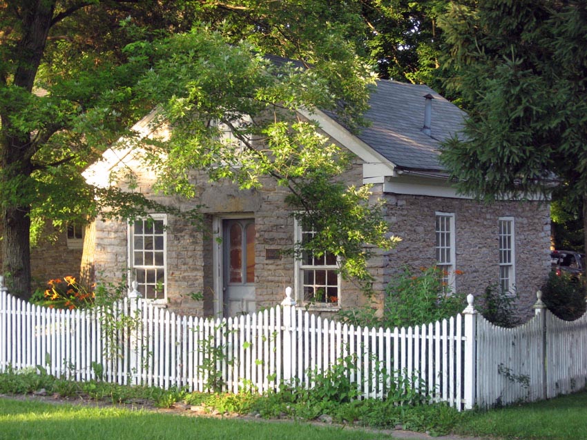Cottage with white picket fence with curved design and decorative posts