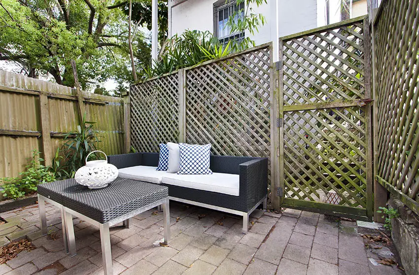 Fence with diamond style lattice and dark grey rattan furniture