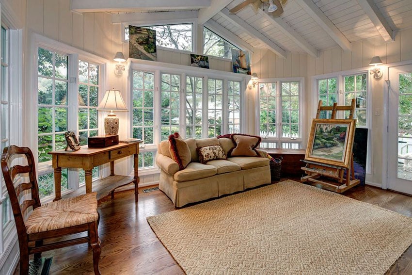 Cozy cottage style sunroom with vaulted ceiling wood floors and views of backyard landscaping