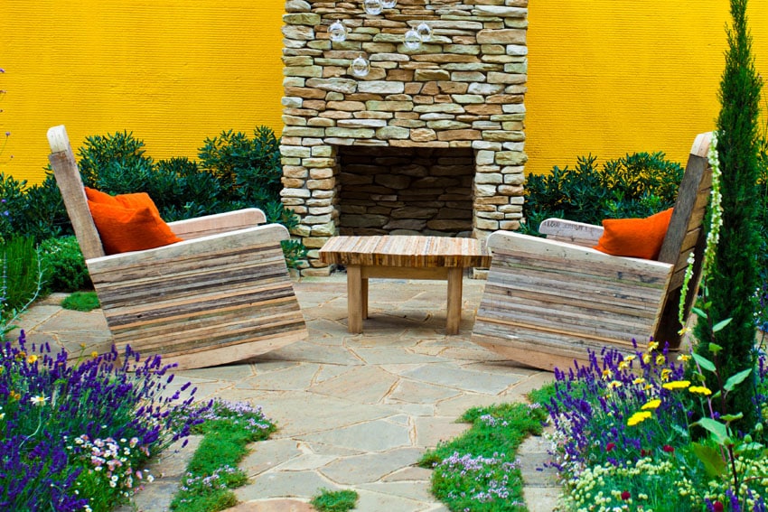 Rustic rocking chairs, outdoor stacked stone fireplace and bright yellow walls