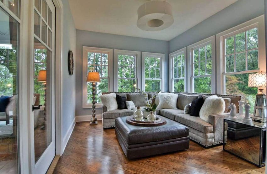 Cozy sunroom with light blue paint l shaped couch and laminate wood floors