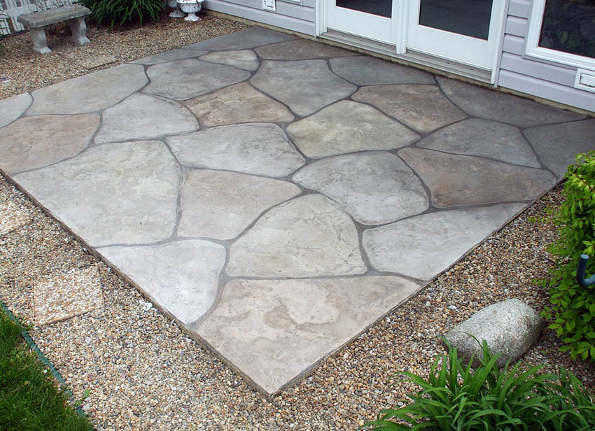 Flagstone design patio made from concrete with gravel border in backyard