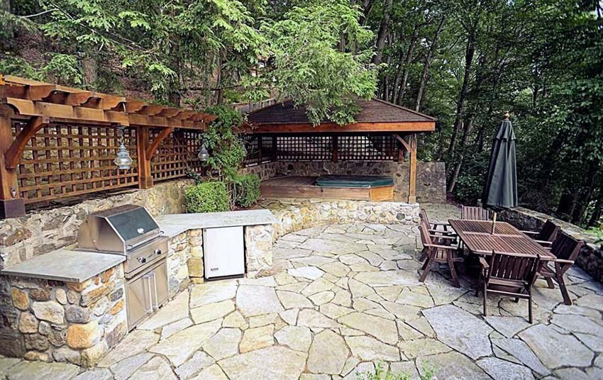 Flagstone patio with outdoor kitchen wood pergola and wood hot tub structure with lattice privacy walls