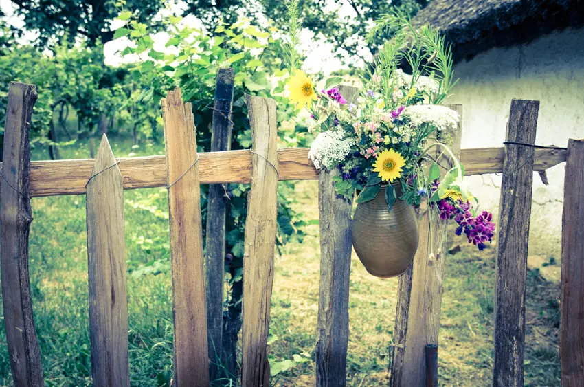 Old wooden fence with hanging vase and cut flowers