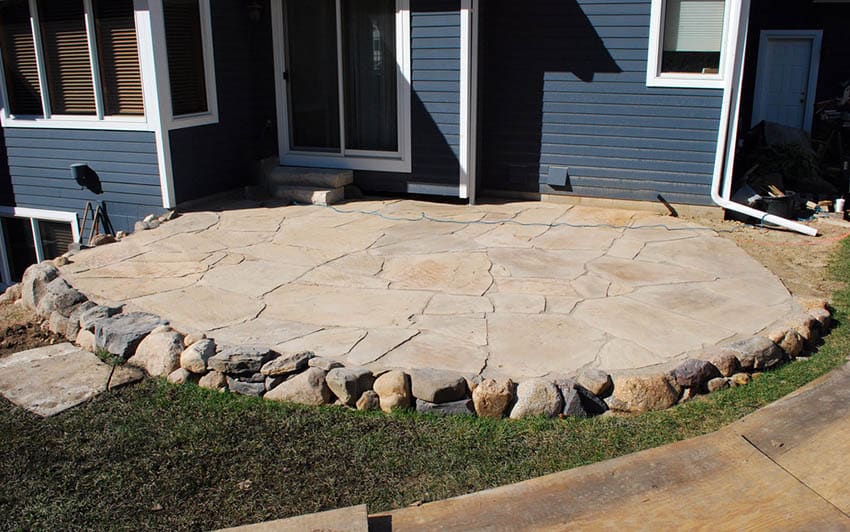 Raised flagstone patio with rock border in backyard