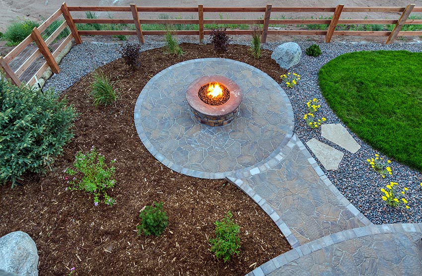 Round flagstone patio with gravel and bark border with fire pit