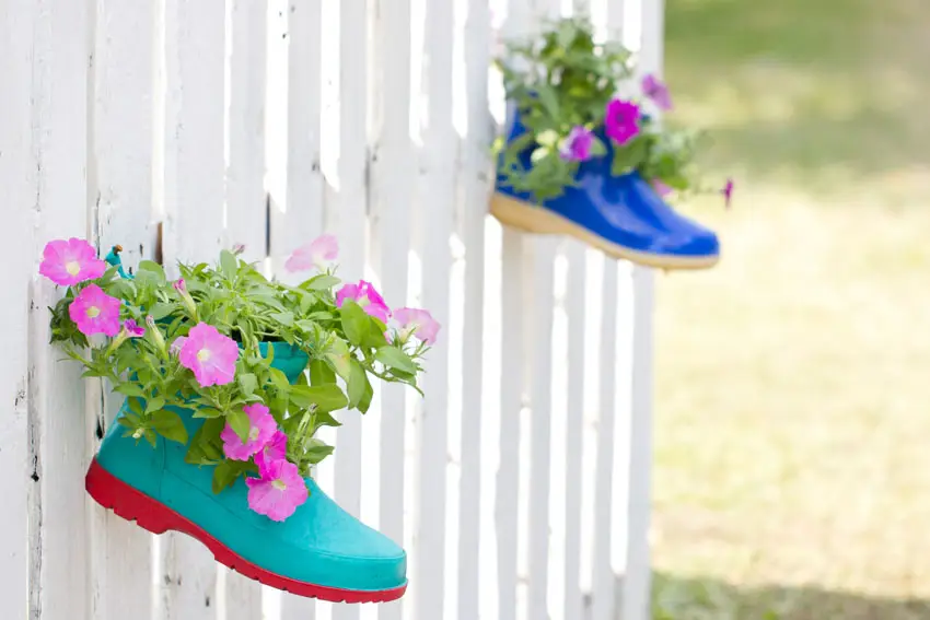 Shoe planters with flowers on fence