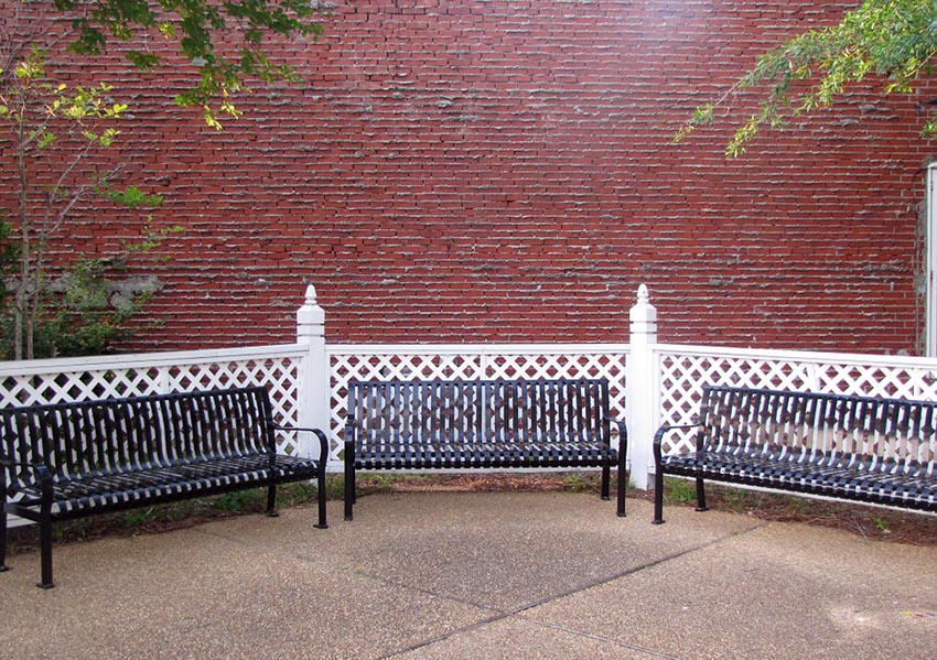 Small white lattice fence with posts and park benches