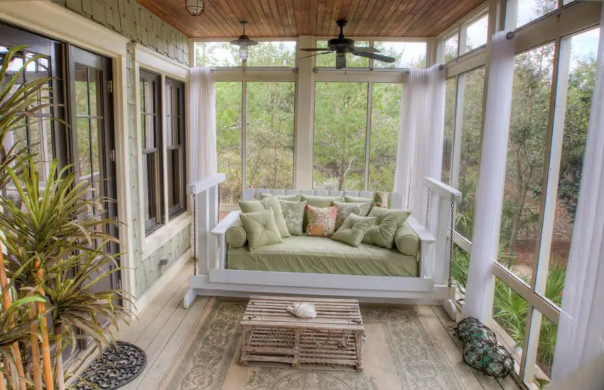 Sunroom add-on with large windows and swinging loveseat