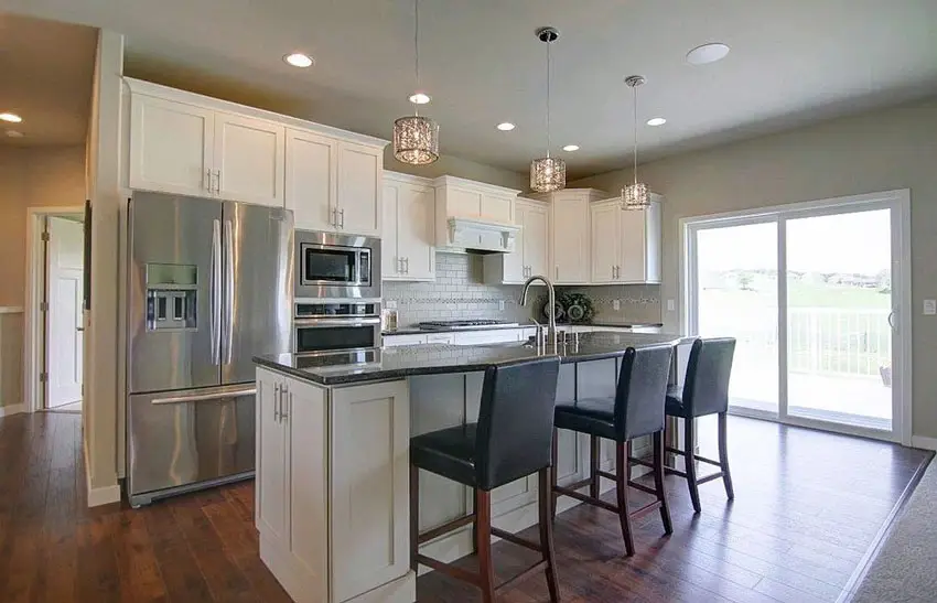 White contemporary kitchen with shaker style cabinets and island with dark countertops