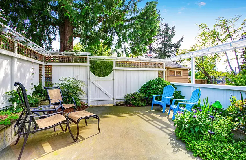 Patio, garden with fence, blue adirondack chairs and narrow pergola