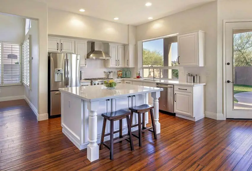 White kitchen with wood breakfast stools and recessed lighting