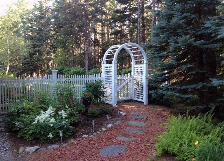 White picket fence with arbor and stone path