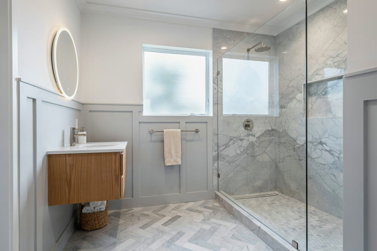 Transitional style bathroom with white ottoman and chevron pattern tiles