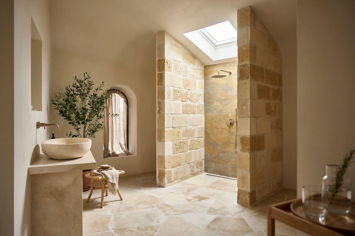 Mediterranean bathroom with stone and golden slate combination for the walls with skylight in the shower area