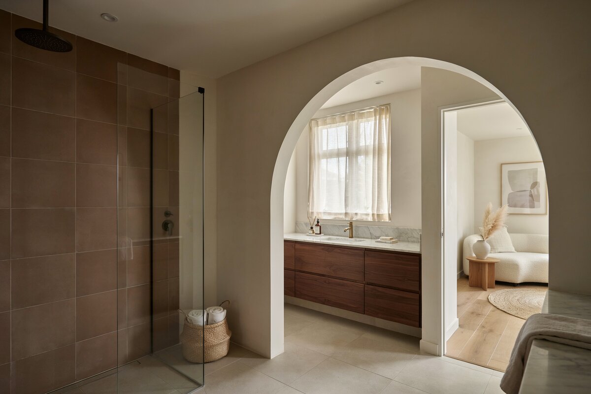 Bathroom with open doorway leading to the living area and shower station clad in brown tiles