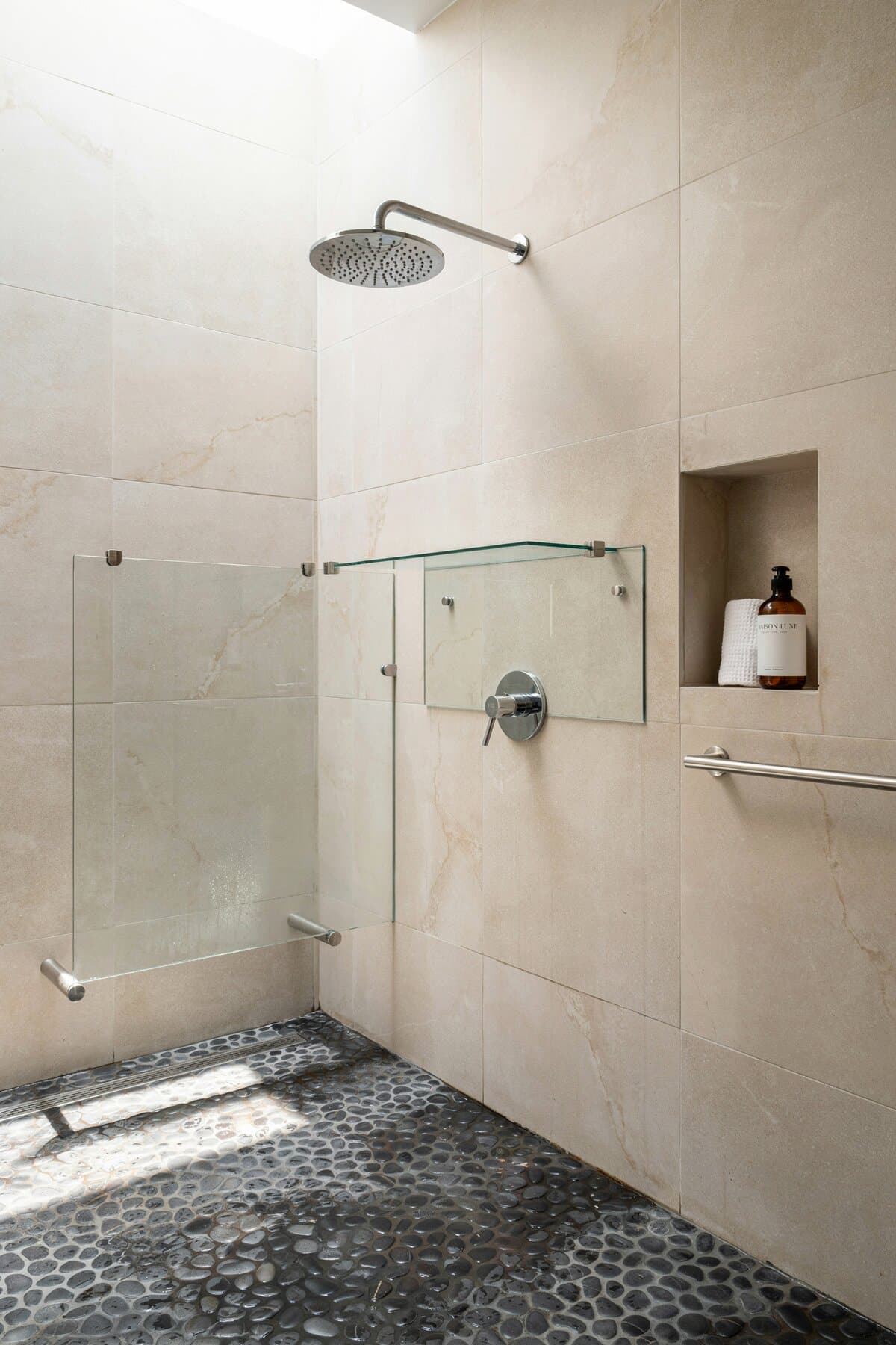 Shower area with half-partition made of glass and chrome bath fixtures