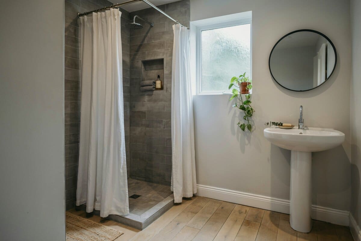 White shower curtains, pedestal sink and mirror