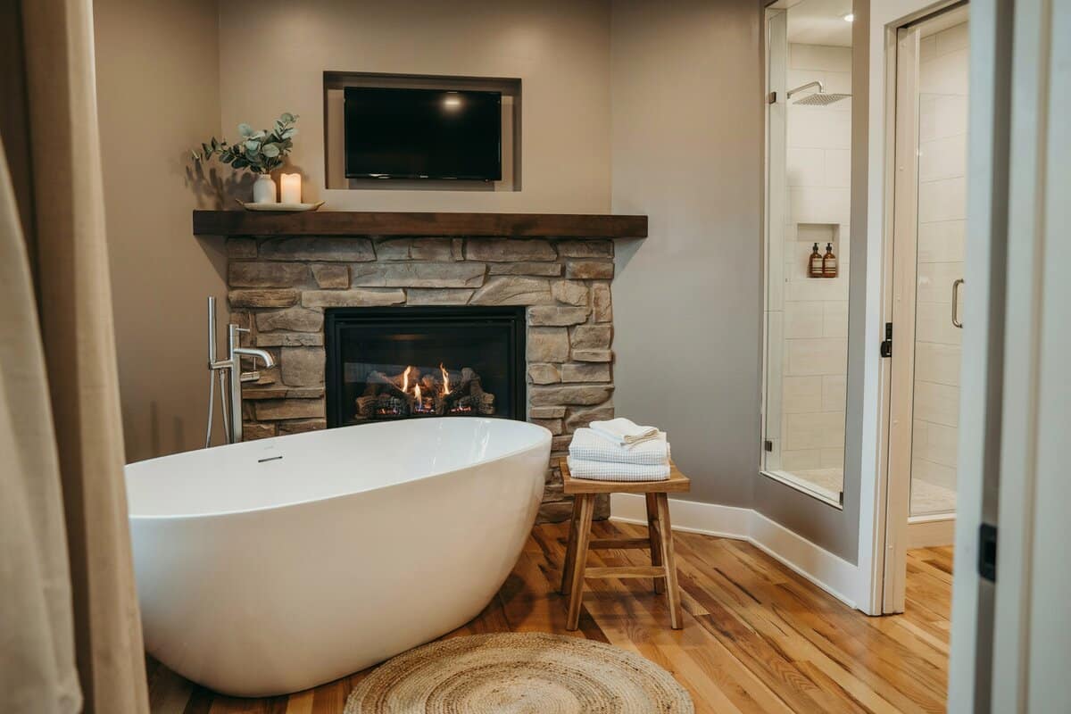 Fireplace and television in front of bathtub with separate shower room