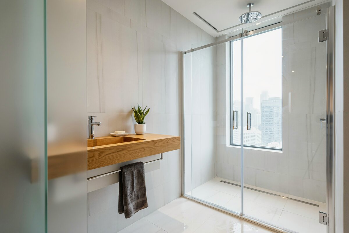 Oatmeal colored walls and shower attached to the ceiling with partial view of the city