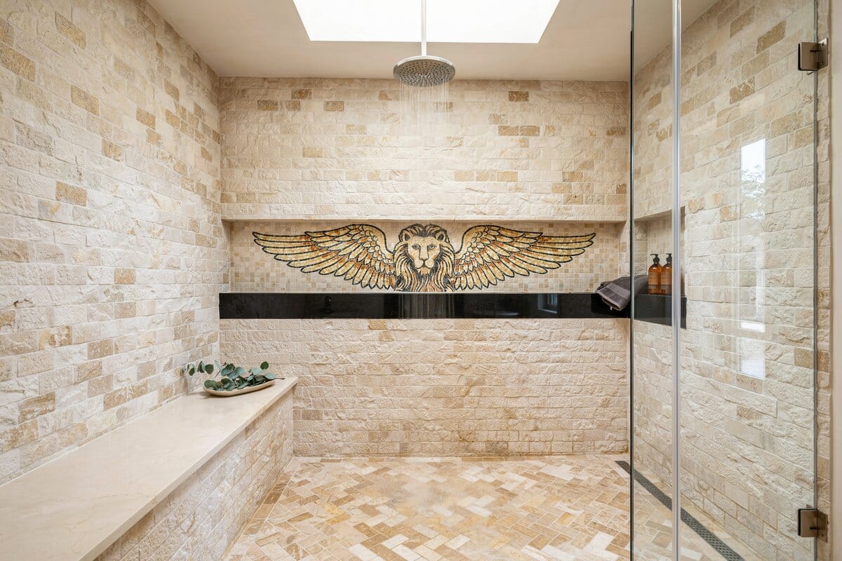 Shower with stacked travertine and mosaic type tiles mural with winged lion wall art
