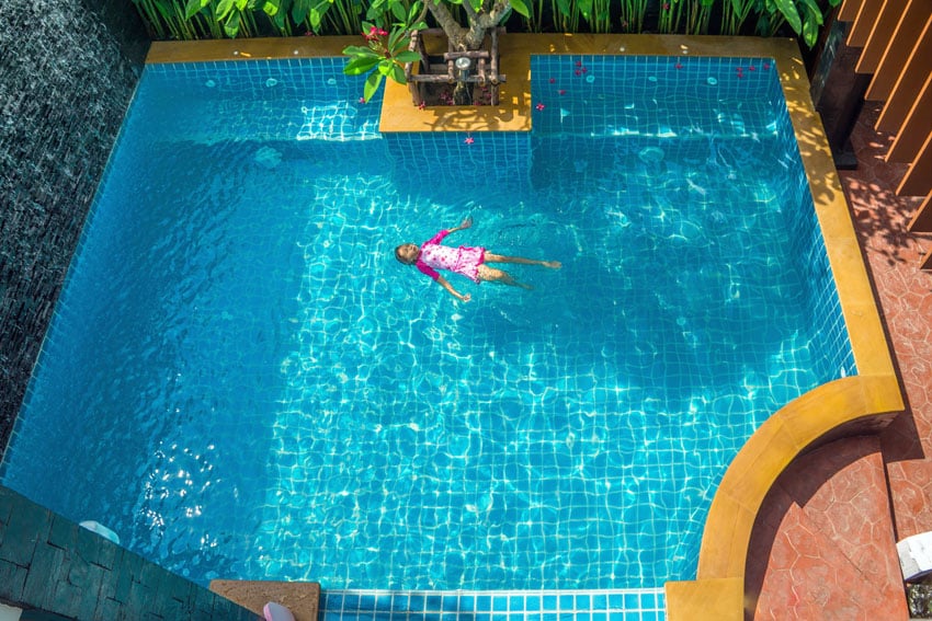 Pool with a few flights of steps and person swimming