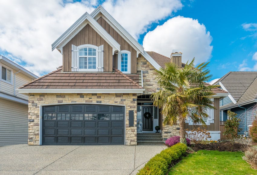 Black colored door for the garage with brick exterior siding