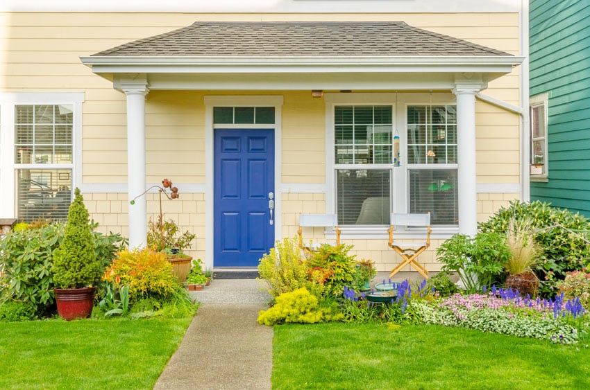 Blue front door on yellow house with flower garden