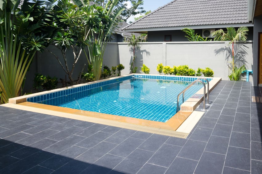 Blue pool with modern tiled patio