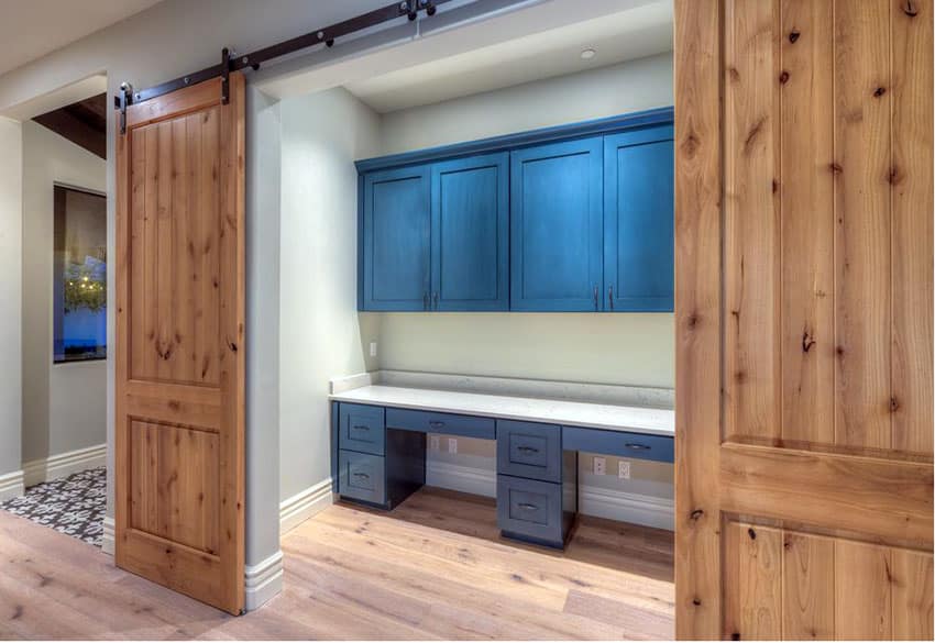 Office with sliding barn doors and blue cabinets