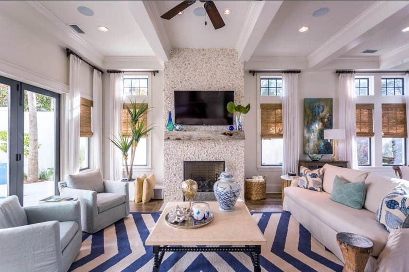 Coastal living room with shell fireplace, beam ceiling and blue jars