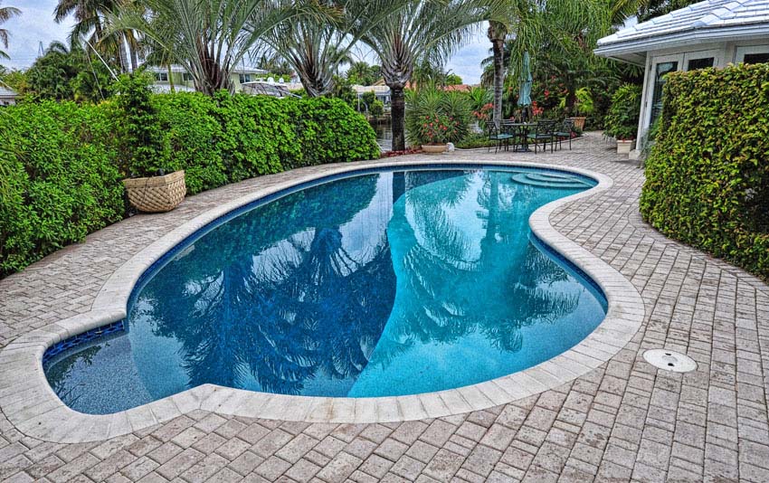 Kidney shaped pool with side sitting area and stone patio