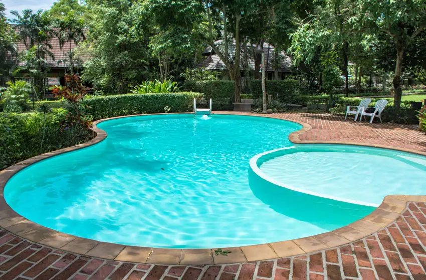 Kidney shaped swimming pool with brick patio