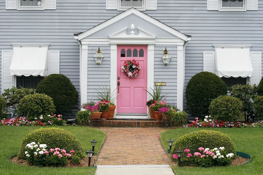 Pink front door on gray house with pink and white flowers