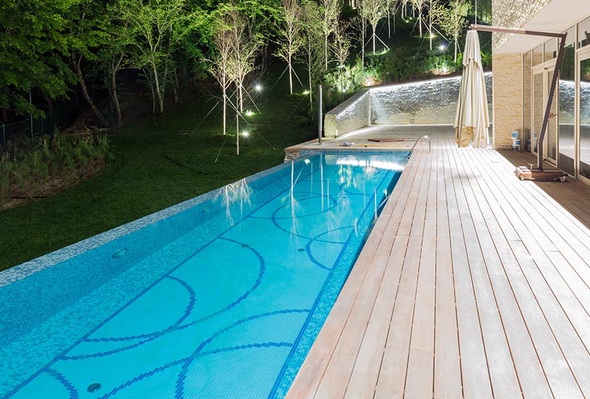 Rectangular swimming pool with curved designs and deck behind modern house