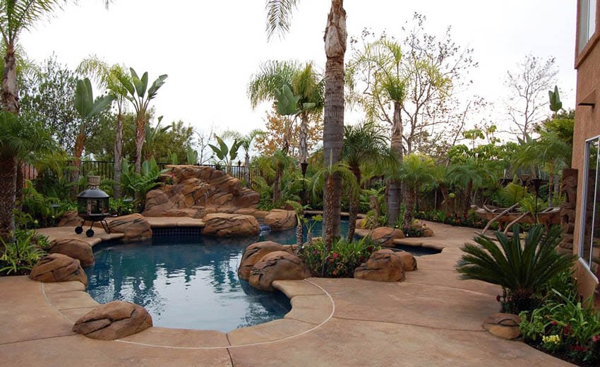 Small dark bottom tile pool with large rocks and palm trees