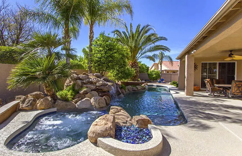 Small rounded swimming pool with fire pit and large boulders