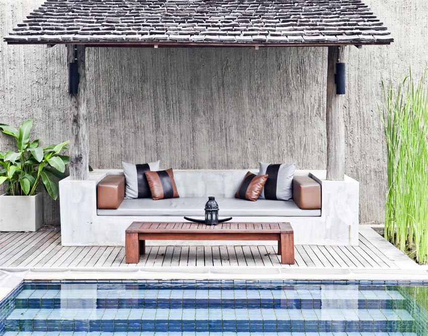 Swimming pool pavilion with concrete couch and thatched roof