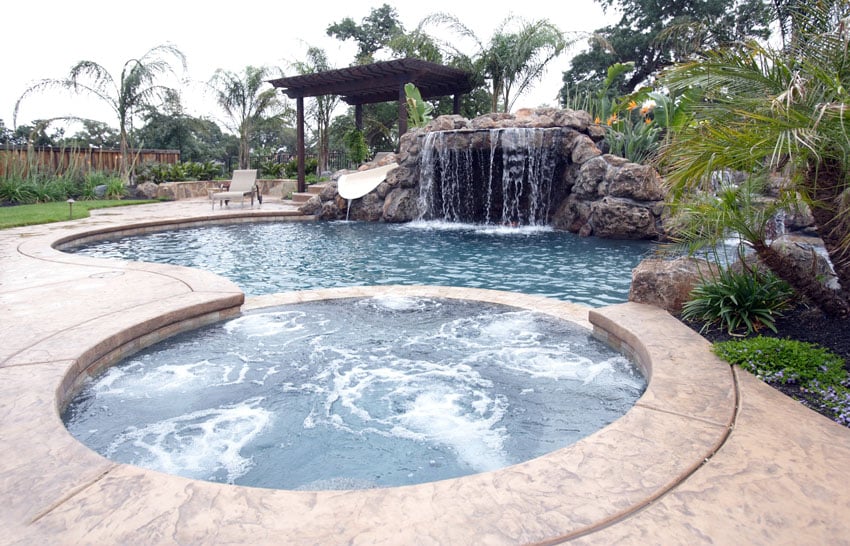 pool with rock slide waterfall and large hot tub